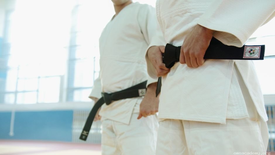 Two martial artists wearing traditional white Taekwondo uniforms and black belts at Om's Martial Arts & Fitness Studio in Jaipur.