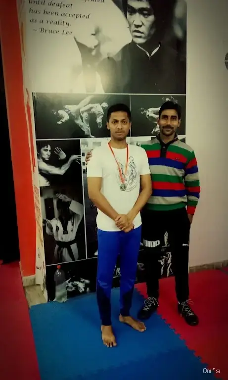 Coaches on the mats with Bruce Lee poster at Om's Academy Jaipur