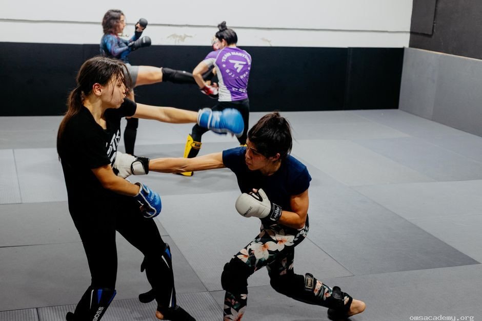 Female students practicing MMA and kickboxing sparring techniques at Om's Martial Arts & Fitness Studio in Jaipur.